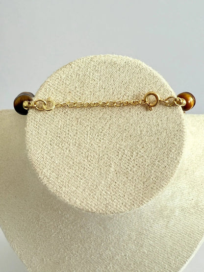 Pulseira de prata banhada a ouro com fecho e pedra natural, exibida em suporte claro.
