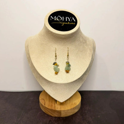 Brincos pendentes com pedras naturais de amazonita em tons verde e dourado, exibidos em suporte bege.