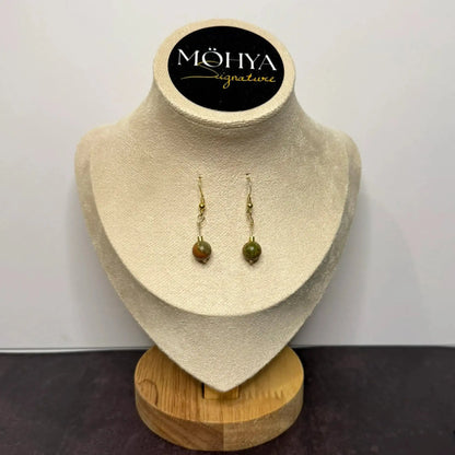 Brincos de prata com pedra unakita esverdeada, exposição em suporte de veludo bege.