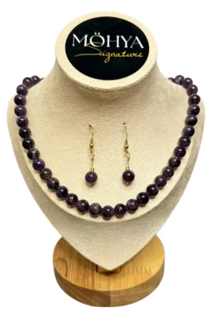Conjunto de colar e brincos artesanais com contas roxas em expositor de joias elegante.